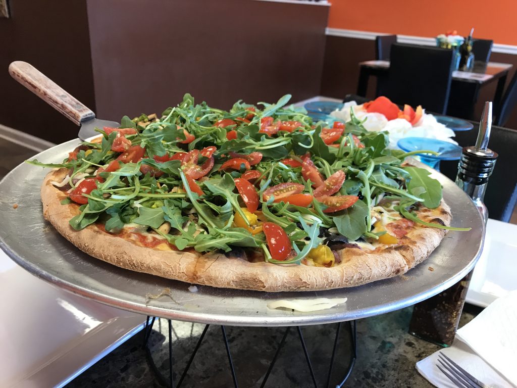 Entire Pizza featuring arugula and cherry tomatoes.